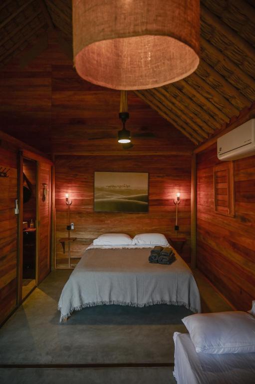 A comfortable double bed beneath a woven pendant light